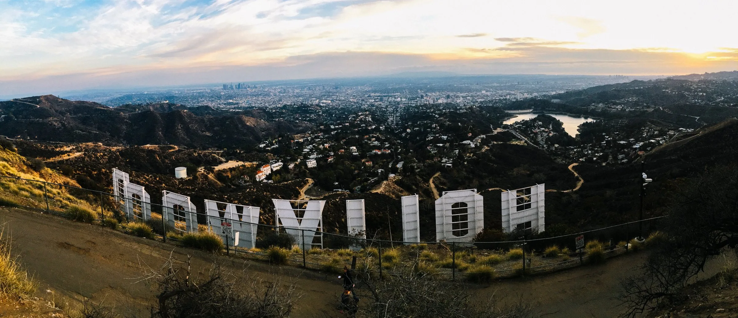 View from behind the Hollywood sign over Los Angeles at golden hour.