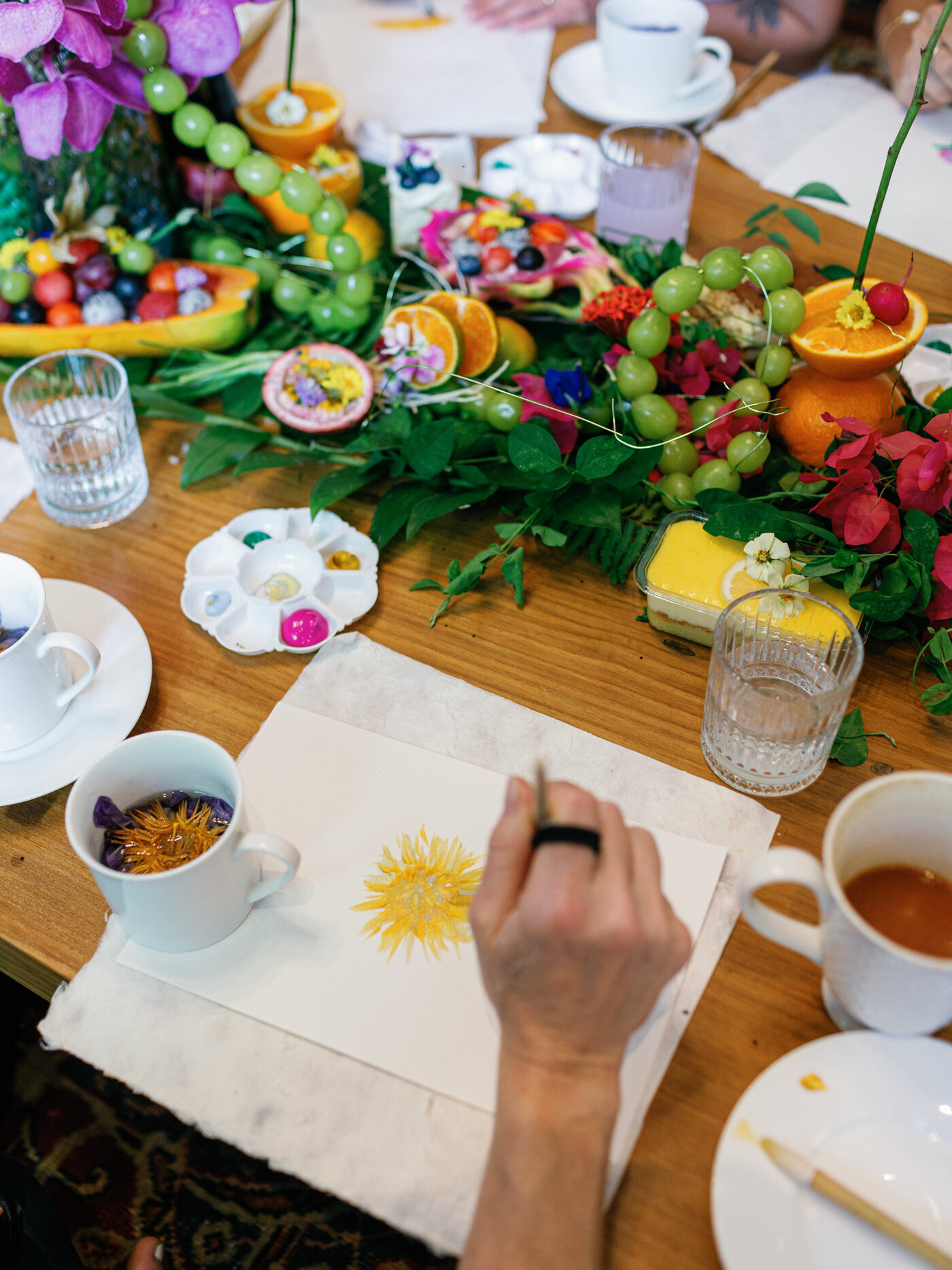 Flowers, fruit, tea, and art materials arranged on a workshop table