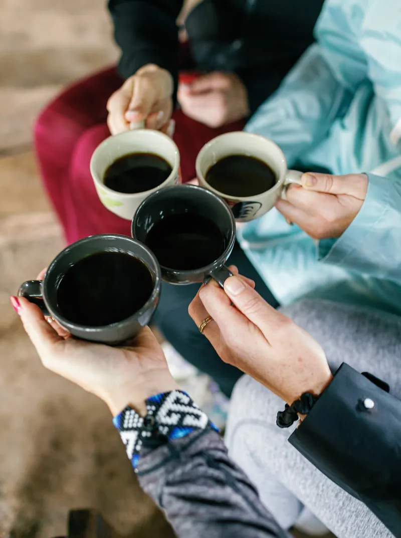 Women toasting with black coffee cups during a morning circle at the Chiang Mai retreat.